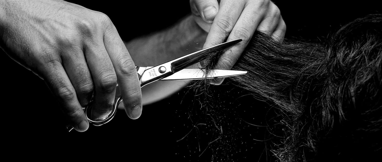 Schere schneidet eine Haarsträhne im Gegenlicht